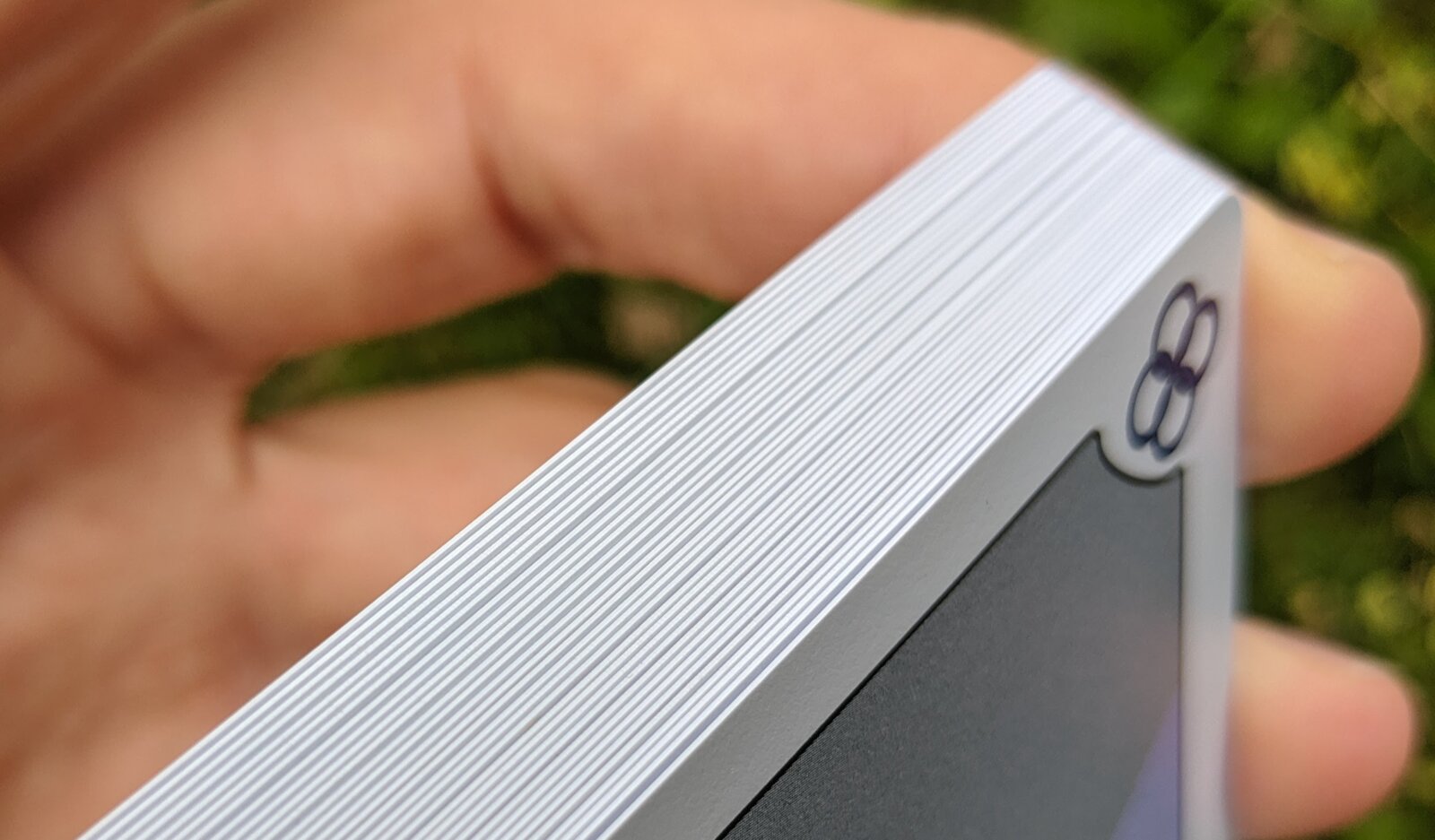 The edge of a Blue Rings deck held in hand, showing the thickness of 32+4 PVC cards